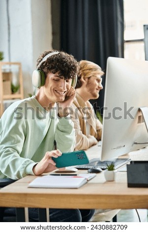 smiling man in headphones taking smartphone near working devices in office space, post production