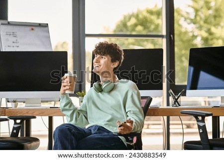 happy young man with headphones sitting in office chair and holding coffee, post production