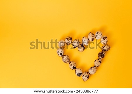 Symbol of love. Heart shape made of marble quail eggs on yellow background. Easter holiday. Business card mockup design. Postcard. Healthy organic food. Empty text place. Proper nutrition. Copy space.