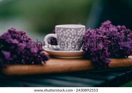 Cup of tea on a wooden board with purple lilac
