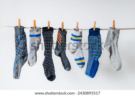 Row of odd socks hanging on clothesline against white background. Royalty-Free Stock Photo #2430895517