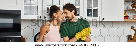 good looking interracial joyous couple enjoying each other while cleaning in kitchen, banner