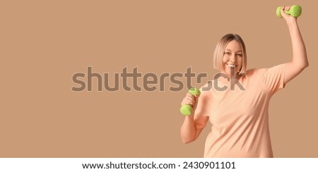 Woman holding dumbbells on beige background with space for text. Weight loss concept