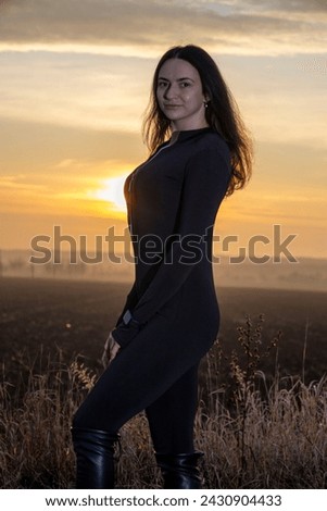 Beautiful young girl in overalls on the background of the sunset.