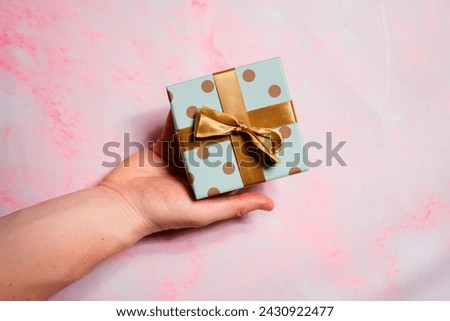 A small gift with a bow held in your hand. Giving a gift to a loved one
