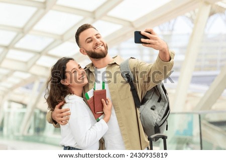 Travel Selfie. Portrait Of Cheerful Young Couple Taking Photos On Smartphone In Airport Terminal, Happy Millennial Man And Woman Posing To Camera With Passports And Tickets In Hands, Free Space