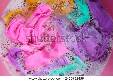 Dirty socks soaked in water, dissolving detergent in basin.