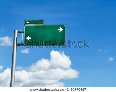 Green traffic sign with white direction arrows on a sunny and cloudy day, signage and directions theme, horizontal image