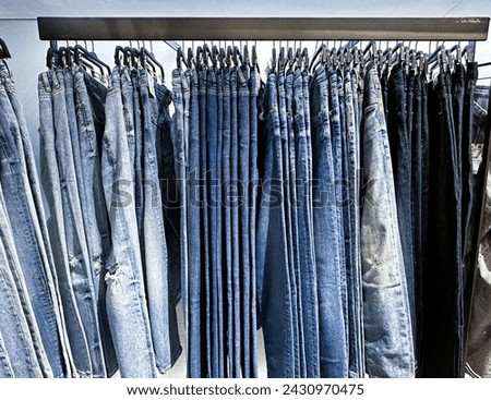 Row of blue Jeans on a hanging rack in the clothes shop store