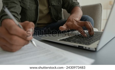 Close up view unrecognizable man male guy working laptop from home browsing internet cropped shot businessman typing computer write notes writing legal document business paperwork pay bills loan taxes