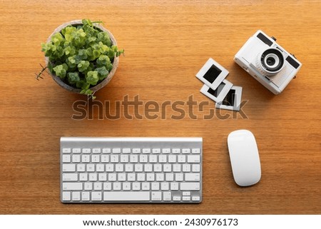 Vintage camera, instant photo frames, keyboard, and mouse are arranged neatly on the office workspace.