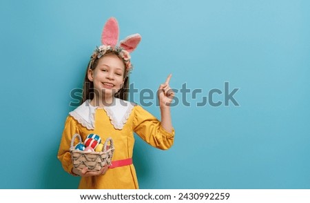 Cute little child wearing bunny ears on Easter day. Girl with painted eggs. Royalty-Free Stock Photo #2430992259