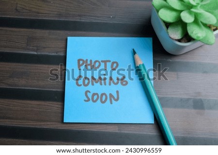 Concept of Photo Coming Soon write on sticky notes isolated on Wooden Table.