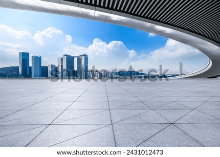 Empty square floor and bridge with city skyline under blue sky