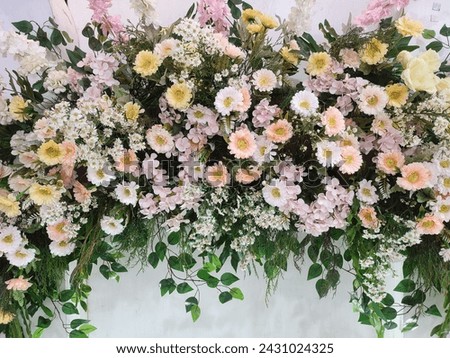 Colorful fake flowers to decorate the aisle.  Curved floral decorations extend over the wedding chairs.  Soft focus. Royalty-Free Stock Photo #2431024325