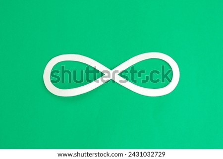 Infinity loop symbol paper cut on bright green background