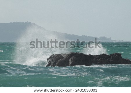 Majestic sea waves crash against a formidable stone within the vast expanse, creating a mesmerizing dance of power and serenity in this captivating coastal moment. Royalty-Free Stock Photo #2431038001