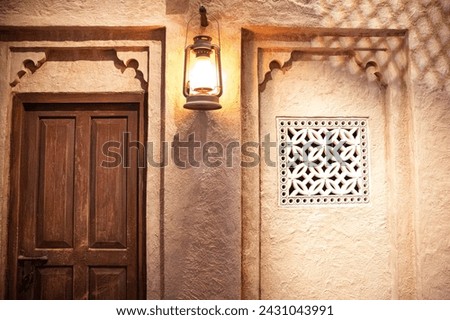 wall of an ancient Arabic house with a carved window and a lantern on the wall Royalty-Free Stock Photo #2431043991