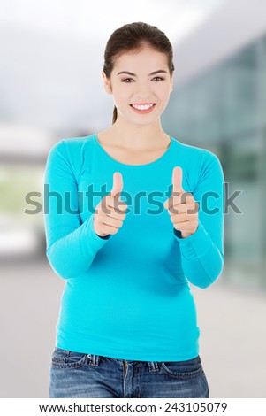 Teen woman in casual clothes gesturing thumbs up