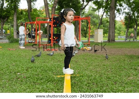  Asia cute girl balancing on steel beams in playground. Concept of enhancing child development.