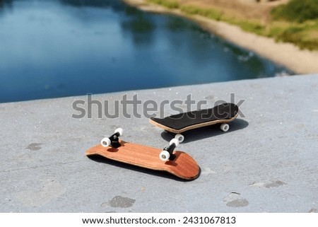 Blank wooden fingerboards at the concrete ledge with river in background. Mini skateboard, small skateboard deck