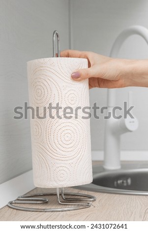 man putting paper towel on kitchen counter. paper towel holder. using a paper towel. vertical photo Royalty-Free Stock Photo #2431072641