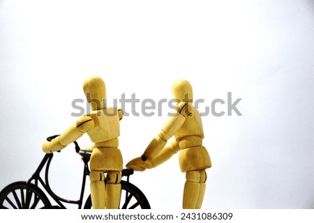 A couple in love is seen walking together while pushing their beloved old bicycle. A wooden mannequin as a model and photographed on an isolated white background. The Concept of falling in love