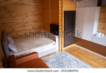 The cabins interior is paneled with wood and furnished with a bed, sofa, and armoire. A bearskin rug adds a touch of warmth to the space. Royalty-Free Stock Photo #2431086941