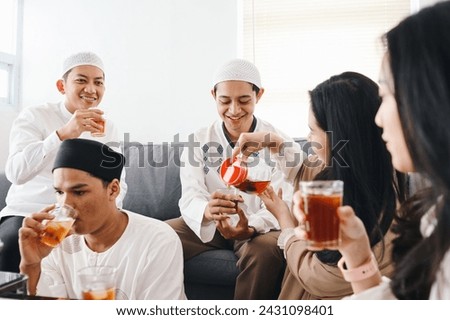 Young Asian muslim people pouring water, having iftar together at home. Break fasting concept. Royalty-Free Stock Photo #2431098401
