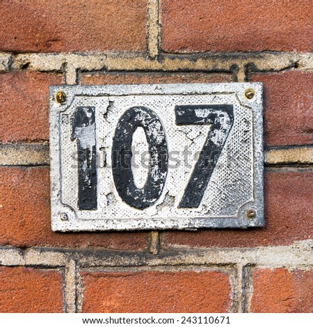 cast metal house number on a red brick wall