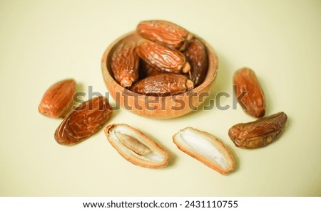 Dried dates fruits in wooden bowl isolated, ramadhan fruits.  Royalty-Free Stock Photo #2431110755