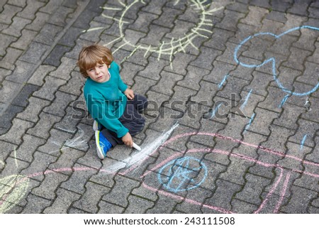 Funny boy of three years painting with colorful chalks outdoors in summer. Kid having fun. Creative leisure with children outdoors.