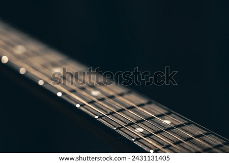 Part of an acoustic guitar, guitar fretboard on a black background. Royalty-Free Stock Photo #2431131405