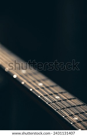Part of an acoustic guitar, guitar fretboard on a black background. Royalty-Free Stock Photo #2431131407
