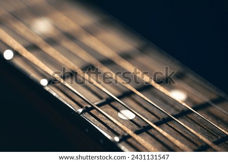 Part of an acoustic guitar, guitar fretboard on a black background. Royalty-Free Stock Photo #2431131547