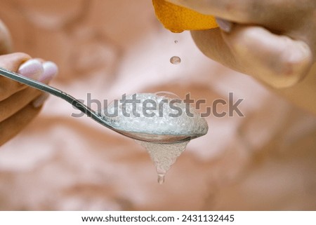 A squeezed drop of lemon juice flying into a spoon filled with baking soda. Abundant foam Royalty-Free Stock Photo #2431132445