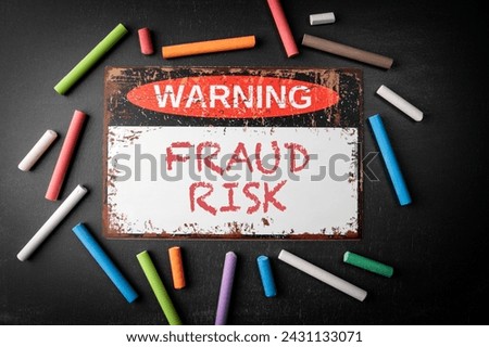 Fraud Risk. Metal warning sign and colored pieces of chalk on a dark chalkboard background.