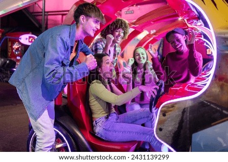 group of multiracial friends having fun playing video arcade and dancing in a night room with neon lights Royalty-Free Stock Photo #2431139299