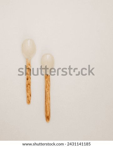 Two Unique Ceramic Spoons with Wooden Handles on a White Surface