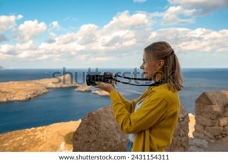 A woman photographer takes pictures of Lindos Bay.