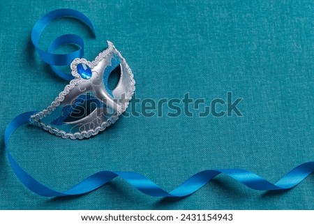 Beautiful carnival masks with a blue ribbon, on a turquoise background. Concept for the holiday Purim, Mardi Gras. View from above