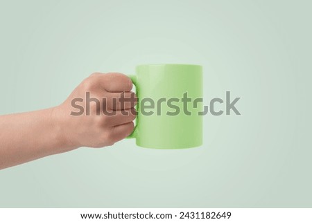 Green cup held in hand with empty surface for branding mockup