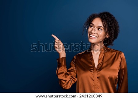 Photo of pretty dreamy woman dressed brown silk shirt eyewear pointing finger looking empty space isolated blue color background