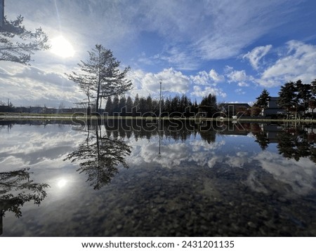 Flooded park in Hokkaido, Japan. The reflection from the water makes for a beautiful picture. You can see the small rocks under the shallow water.