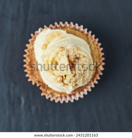 Beautiful inviting rustic gourmet Sponge and cream cup cakes with a shallow depth of field, photographed on a grey slate table. Sprinkles and sweet sugary crumble.