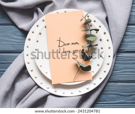 The image is of a cake on a plate with a handwritten note that says "Dear mom, I love you." It includes tags such as text, tableware, handwriting, food, and plate.