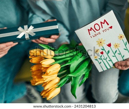 The image is of a person holding a sign that says "MOM I LOVE YOU." The person is wearing clothing and there is a flower visible in the image.