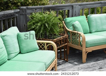 Wooden patio chairs on a large deck with bright green cushions.