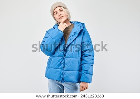 Woman in winter attire with a pensive expression, isolated on a light background.