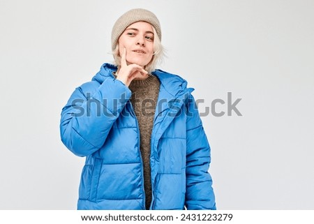 Woman in winter attire looking thoughtful against a light background.